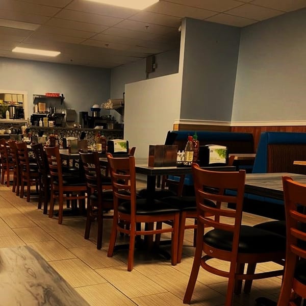 Interior of Pho Huyen & Banh Mi, showing rows of empty tables and chairs in a casual dining area.