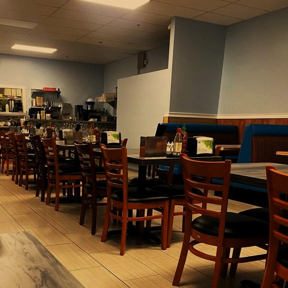 Interior of Pho Huyen & Banh Mi, showing rows of empty tables and chairs in a casual dining area.