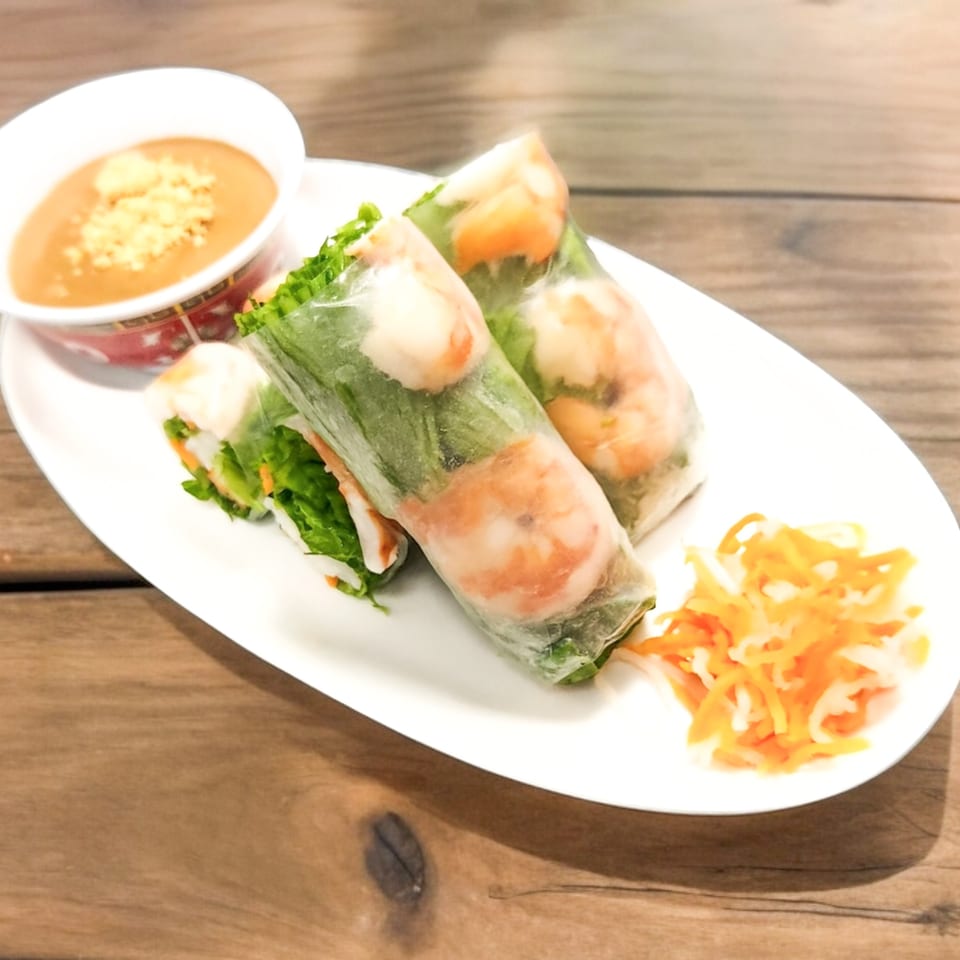 Fresh Vietnamese spring rolls with shrimp and vegetables, served with peanut dipping sauce and pickled carrots.