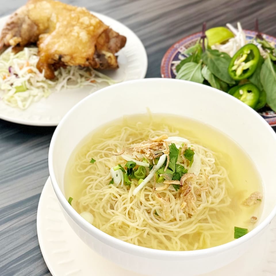 Vietnamese egg noodle soup with fried chicken and a side of fresh herbs and jalapeños.