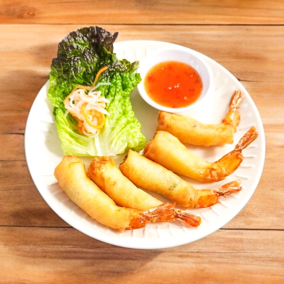 Five crispy Vietnamese shrimp spring rolls with lettuce, pickled vegetables, and sweet chili sauce.